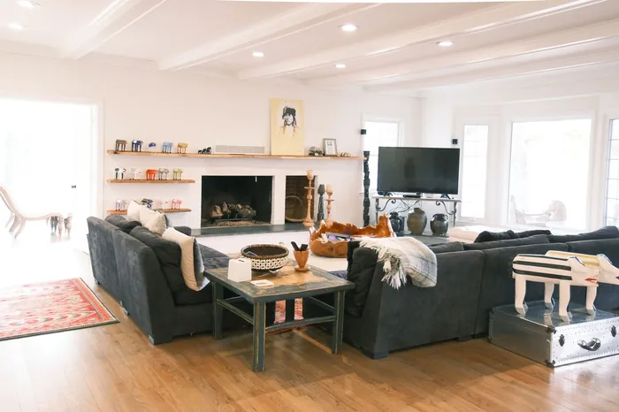 The Farmhouse living room at The Horse Shoe Farm featuring a stone fireplace, charcoal sectional, built-in shelving, and warm oak floors