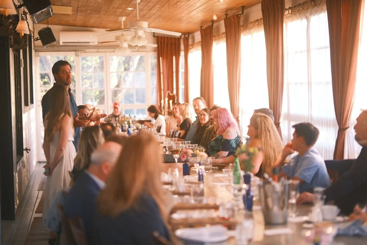 Guests seated along one long candlelit table inside the barn at The Horse Shoe Farm
