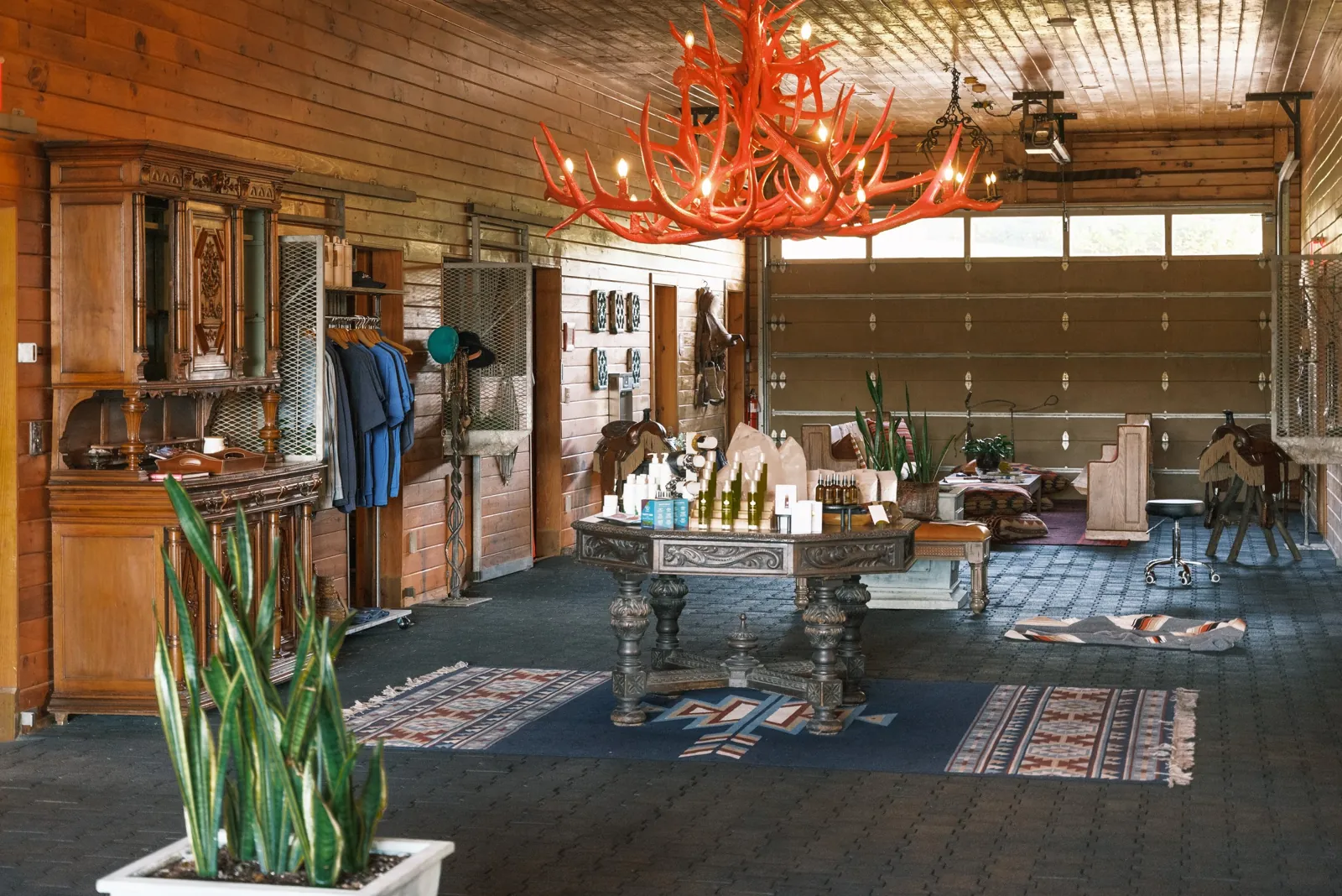 The Stable Spa lounge inside a renovated barn with timber beams, antler chandelier, and layered rugs
