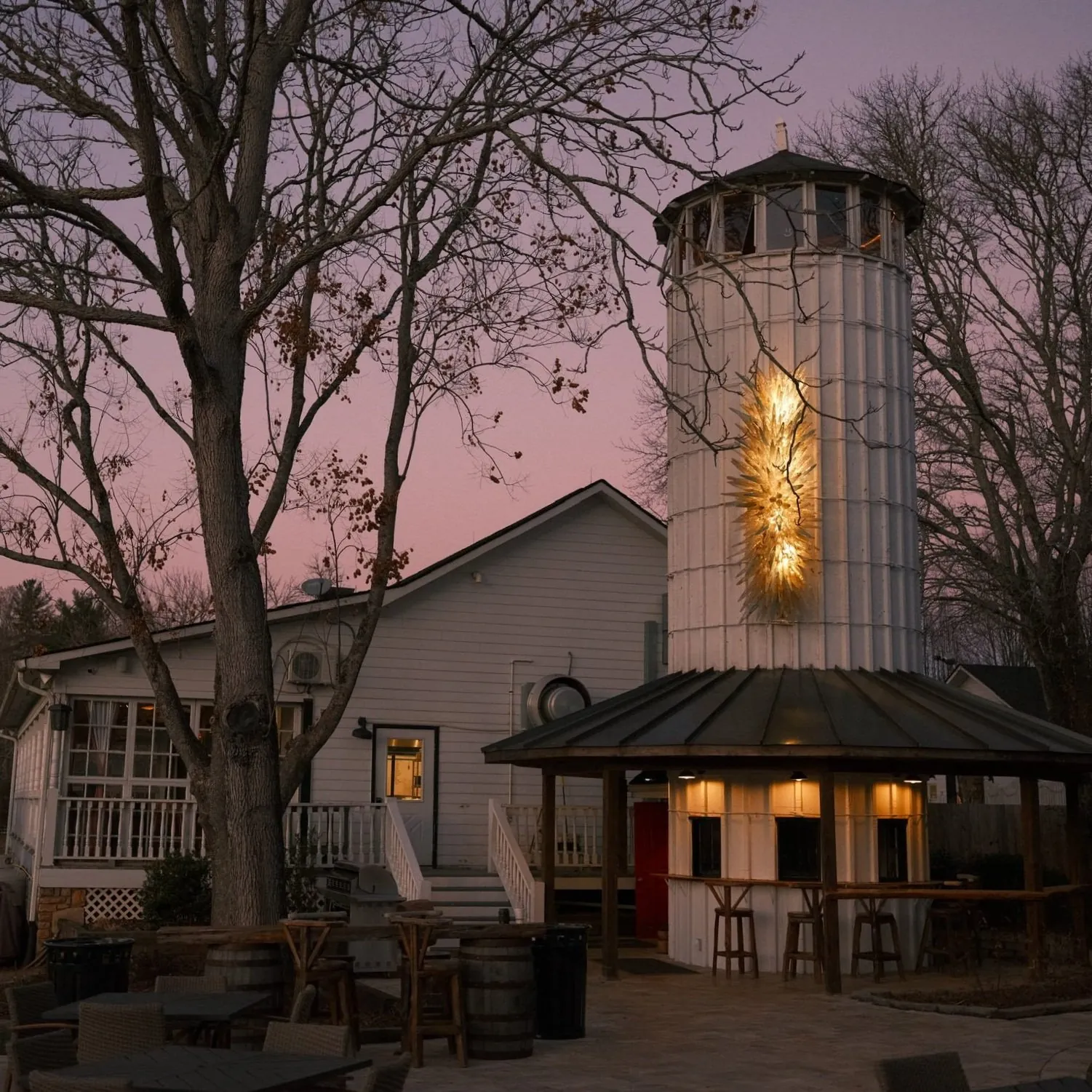 The Silo Cookhouse lit from within at dusk under a pink and blue sky