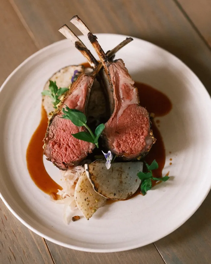 A rack of lamb plated with jus and microgreens at the Silo Cookhouse, the on-property farm-to-table restaurant